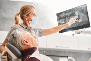 A close up image of a dentist placing an oral implant into a patient's mouth, with dental tools visible. No text on image.