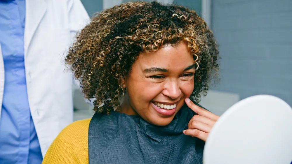 A periodontist examining a patient's mouth, focusing on the gums, using specialized dental instruments. No text on image.