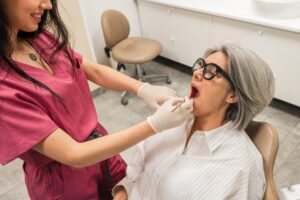 Photo of a dentist showing a patient a model of different options for tooth replacement, including a dental implant, bridge, and partial denture. No text on the image.