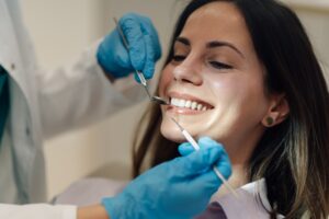 A periodontist examining a patient's mouth, focusing on the gums, using specialized dental instruments. No text on image.