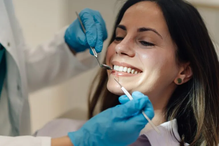 A periodontist examining a patient's mouth, focusing on the gums, using specialized dental instruments. No text on image.